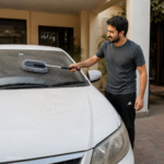 Microfiber car duster reaching the car windshield with its telescoping handle