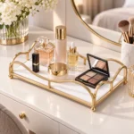 Gold mirror finish vanity tray with perfume bottles and florals on a bright vanity